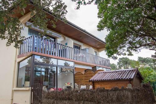 une maison avec un balcon au-dessus dans l'établissement Les Genêts, à Mimizan-Plage