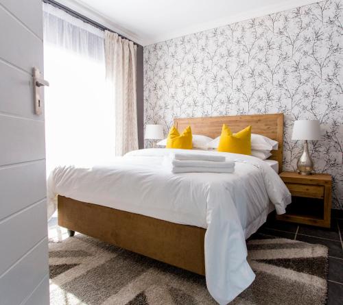 a bedroom with a large bed with yellow pillows at 3 Lux Suites in Middelburg