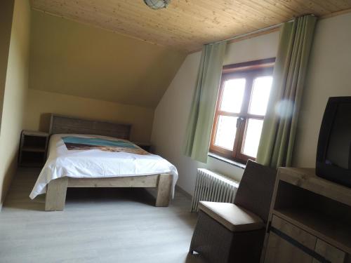 a bedroom with a bed and a window and a television at Vakantiehuis " Te Lande " in Torhout