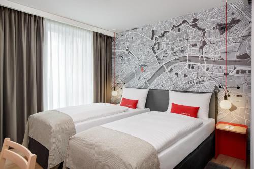 a hotel room with two beds with red pillows at IntercityHotel Frankfurt Hauptbahnhof Süd in Frankfurt
