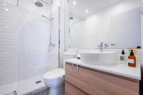 uma casa de banho branca com um lavatório e um WC em Ria Beach House em Faro