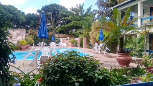 a pool with chairs and umbrellas next to a house at Pousada Mucugê in Mucugê