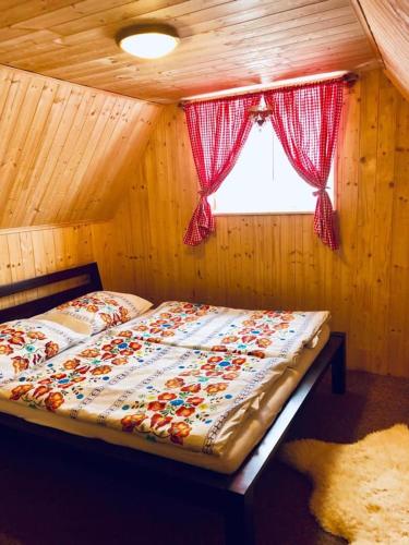 a bed in a wooden room with a window at Chalúpka v Ždiari in Ždiar