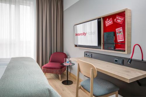 a hotel room with a bed and a desk and a tv at IntercityHotel Frankfurt Hauptbahnhof Süd in Frankfurt