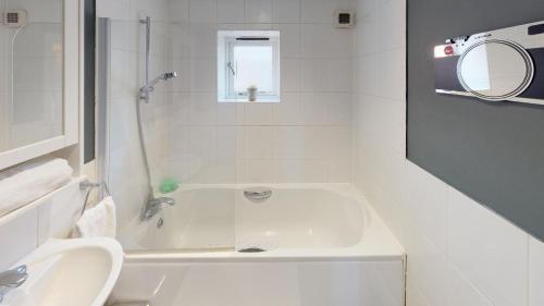 Baño blanco con bañera y lavamanos en Little Bury Barn en Bury Saint Edmunds