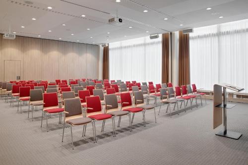 a conference room with red chairs and a podium at IntercityHotel Frankfurt Hauptbahnhof Süd in Frankfurt/Main