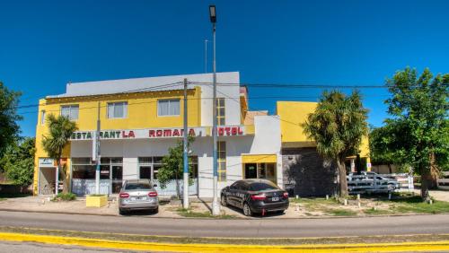 a yellow building with two cars parked in front of it at La Nueva Romana in Santa Clara del Mar