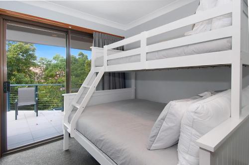 a white bunk bed in a room with a balcony at Byron Bay Accom Calinda Sol 7 in Byron Bay
