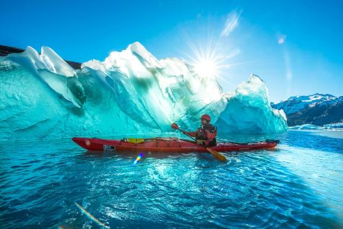 a man in a kayak in front of an iceberg at Kau Lodge in Puerto Natales