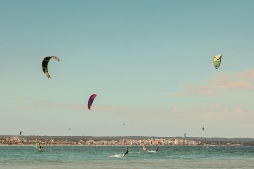 a group of people flying kites in the water at Caramelo Palma Beach in Playa de Palma