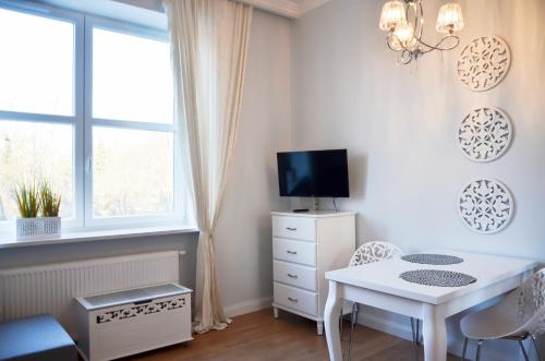 a small white room with a table and a tv at Gagarina 33 - studio by Homeprime in Warsaw