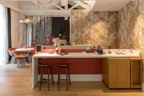 a kitchen with a counter and a bar with stools at Yndo Hôtel in Bordeaux