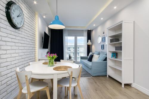 a kitchen and living room with a white table and chairs at Elite Apartments Marine Cztery Oceany in Gdańsk
