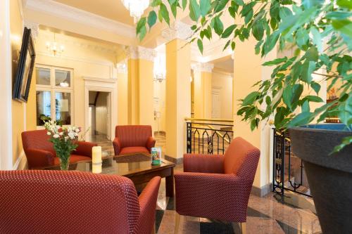 a lobby with red chairs and a table and a plant at Palais am Kleistpark in Frankfurt/Oder