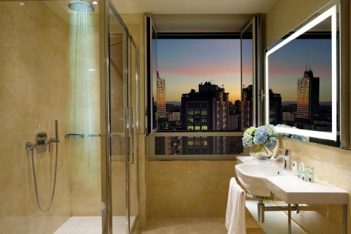 
a bathroom with a large mirror and a large window at UNAHOTELS Century Milano in Milan
