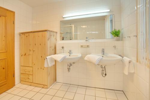 La salle de bains est pourvue de 2 lavabos et d'un miroir. dans l'établissement Zum See, à Ofterschwang
