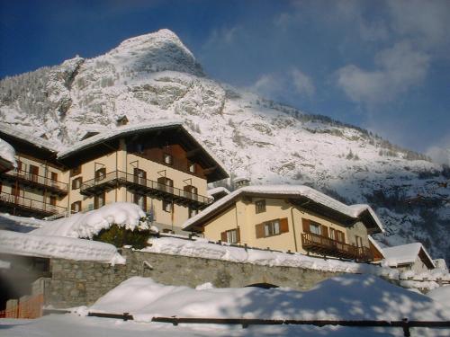 a snow covered building with a mountain in the background at Hotel Ottoz Meublé in Courmayeur