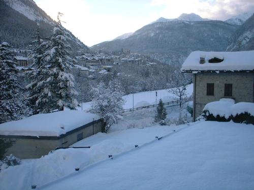 a house covered in snow next to a mountain at Hotel Ottoz Meublé in Courmayeur