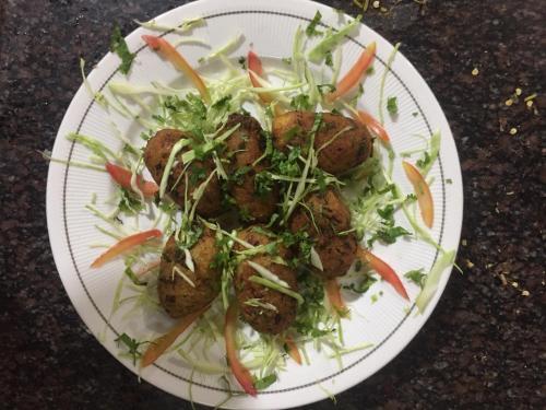 een bord eten met gehaktballen en salade erop bij Vela Resort in Pushkar