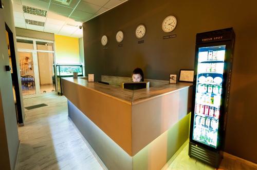 a woman sitting at a counter in a store with clocks on the wall at Bedway Athens Hostel in Athens