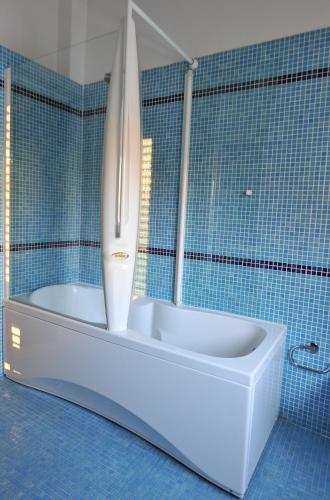 a bathroom with a bath tub in a blue tiled room at Hotel Britannia in Cesenatico