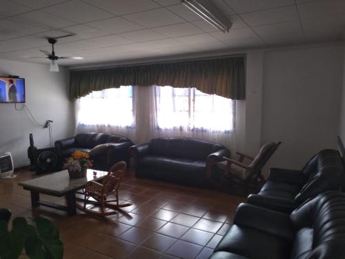 uma sala de estar com sofás de couro preto e uma mesa em Hotel Nevada Ubatuba em Ubatuba