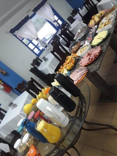 a table with plates of food on top at Hotel Nevada Ubatuba in Ubatuba
