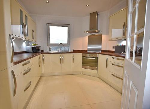 uma grande cozinha com armários brancos e uma janela em 12 Lochiel Road em Fort William