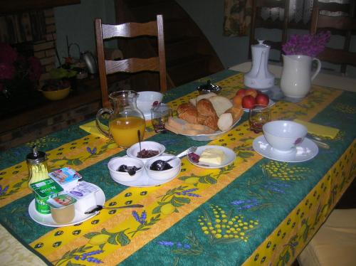 a table with a breakfast of bread and fruit on it at Au Clos du Logis in Maintenay