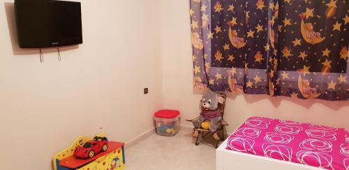a small room with a bed and a tv at Appartement de luxe centre ville les "Dunes d'Or" in Oujda