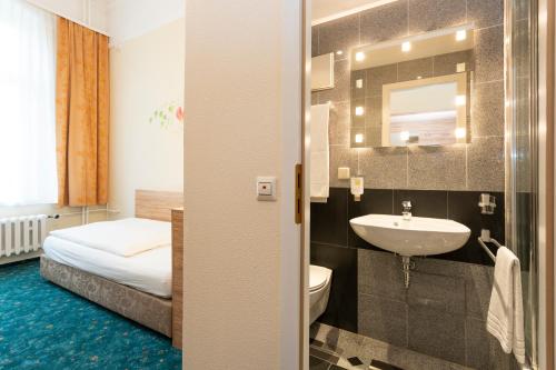 een badkamer met een wastafel, een toilet en een bed bij Palais am Kleistpark in Frankfurt/Oder