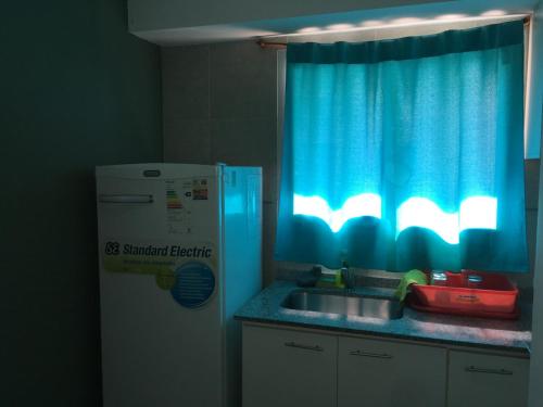 uma cozinha com um lavatório e uma cortina azul em Guadalupe Apart em Santa Fé