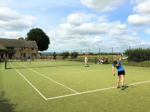 a group of people playing tennis on a tennis court at Banbury Hill Farm Bed & Breakfast in Charlbury