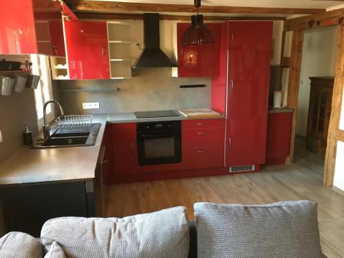 una cocina con armarios rojos y 2 sillas. en Les Gîtes du Racème, en Blienschwiller