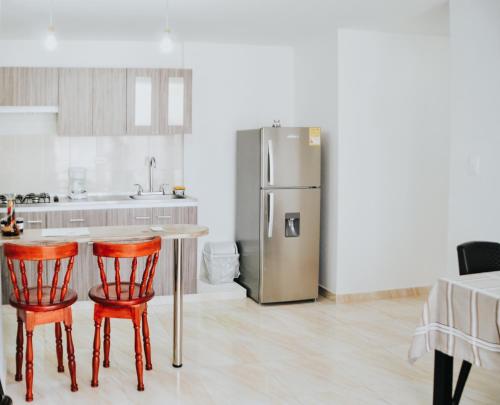 cocina con mesa, 2 sillas y nevera en Bello Apartamento 2 alcobas en Buga