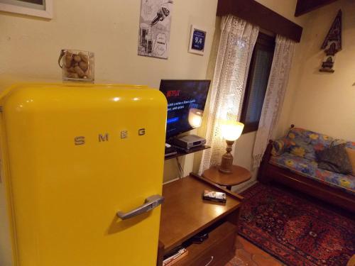 a yellow refrigerator in a living room with a tv at Chalé no Centro de Canela in Canela