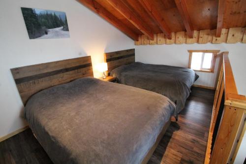 two beds in a room with wooden floors at Red Cariboo Apartments in Anahim Lake