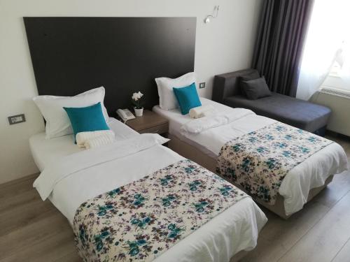 a hotel room with two beds and a chair at Atlas City Center Hotel in Prilep