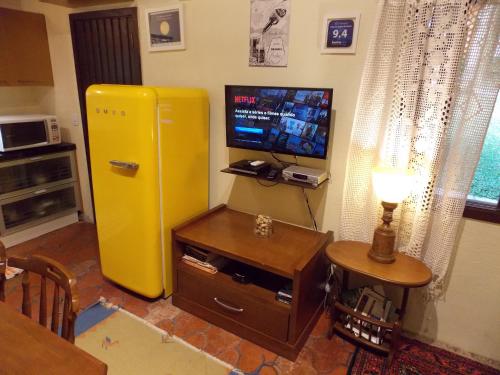 a living room with a yellow refrigerator and a television at Chalé no Centro de Canela in Canela