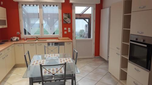 une cuisine avec une table et des chaises dans une cuisine dans l'établissement Le Gîte du Magnolia, à Willerval