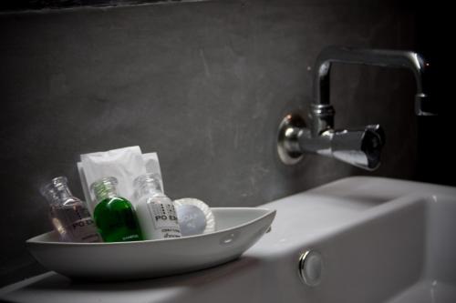 ein Waschbecken im Badezimmer mit einer Schüssel mit Alkoholflaschen darauf in der Unterkunft De Poem Loft Boutique Residence in Hat Yai