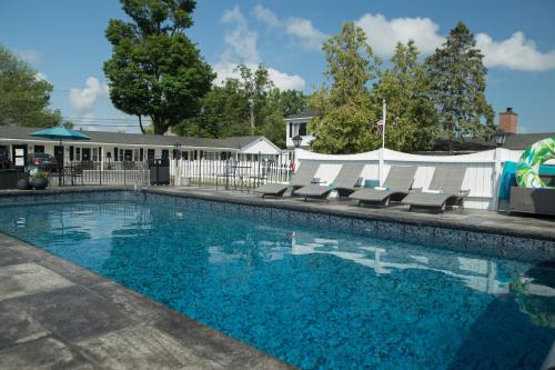 a large swimming pool with chairs and a building at Knotty Pine Motel in Bennington