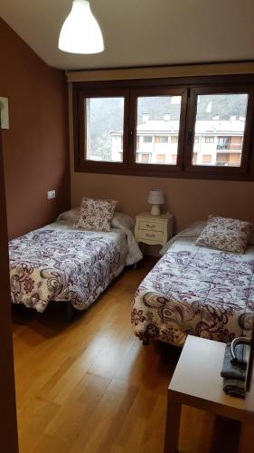 1 dormitorio con 2 camas y 2 ventanas en El Balcón del Sella, en Cangas de Onís