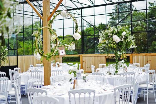 a wedding reception in a greenhouse with white tables and chairs at Château du Bois-Guy in Parigné