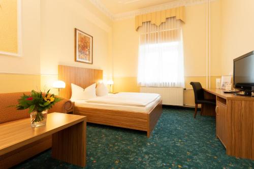 a hotel room with a bed and a television at Palais am Kleistpark in Frankfurt/Oder