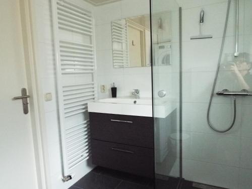 een witte badkamer met een wastafel en een douche bij Wad'n Dream in Moddergat
