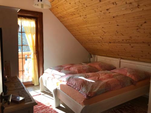 a bed in a bedroom with a wooden ceiling at Rekreačný zrubový dom in Liptovský Trnovec