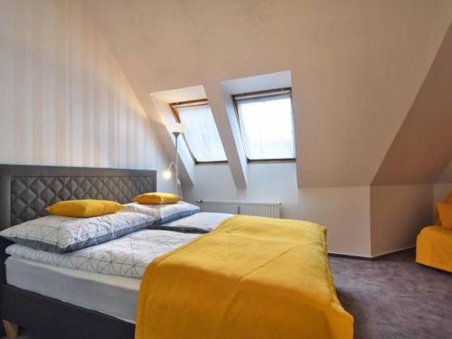 コウォブジェクにあるPiasek i Woda Apartament w Porcieのベッドルーム1室(黄色いシーツ付きのベッド1台、窓2つ付)