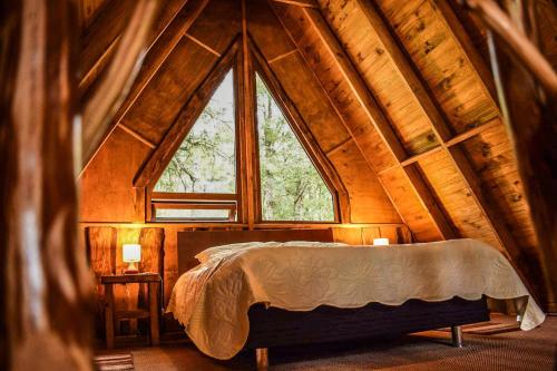 Bett in einem Zimmer mit einem großen Fenster in der Unterkunft Cabañas Ecoturismo la Pancha in Puerto Aisén