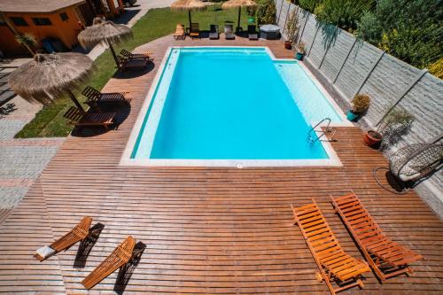 a swimming pool on a wooden deck with chairs and umbrellas at Cajón del Maipo Lodge in San José de Maipo